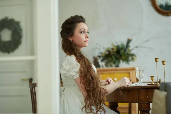 Krásná Žena Dlouhými Vlasy Dlouhých Bílých Šatech Sedí Stolu Dívá — Stock fotografie