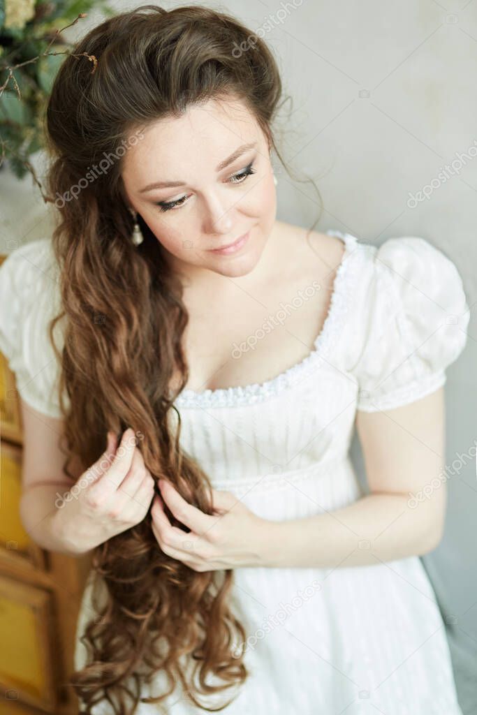 Beautiful woman with long hair in a long white dress. Stands and looks to the side. Historical reconstruction