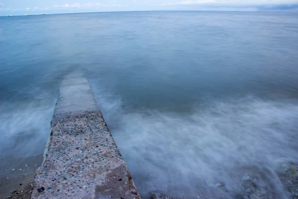 A onda do mar com o pilar que se estende para o mar . — Fotografia de Stock