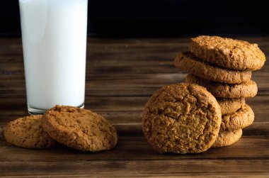 Tahta yüzeyde bir grup yulaf değirmeni kurabiyesi ve süt bardağı - yakın çekim