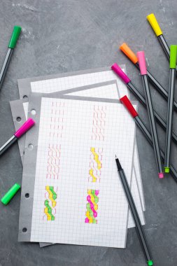 Masanın üzerinde renkli kalemlerle çizim yapmak için kağıt var..