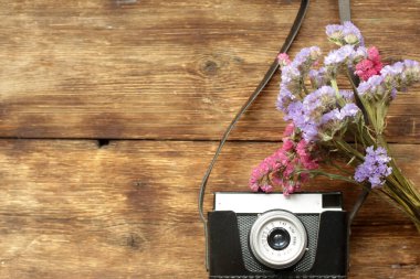Ahşap bir masanın üzerinde çiçekli bir kamera var..