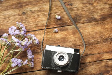 Ahşap bir masanın üzerinde çiçekli bir kamera var..