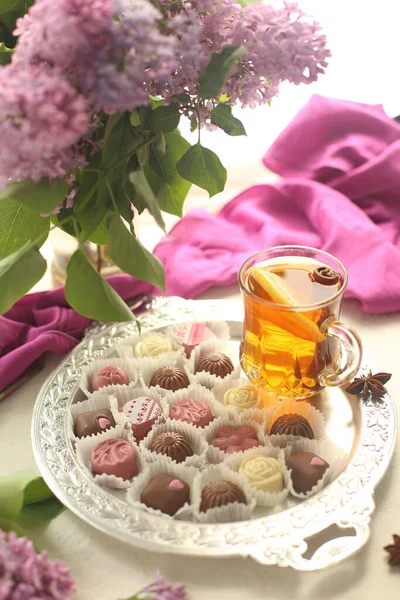 On a silver tray are sweets, sweets and a cup of tea with lemon.