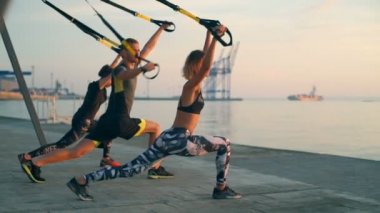 Trx sahil, güneş doğarken eğitim güzel sportif insanlar. Ağır çekim.