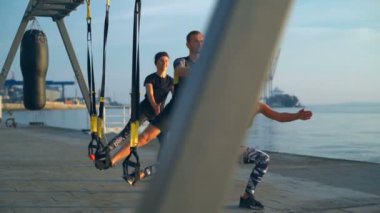 Sportif insanlar doğarken ağız kavgası trx deniz kenarında ile eğitim. Ağır çekim.