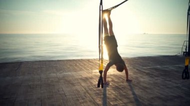 Trx katta güneş doğarken eğitim sportif adam silüeti. Ağır çekim.