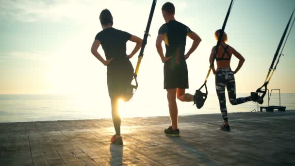 TRX® workout op een terras in de buurt van de zee bij zonsopgang slow motion — Stockvideo