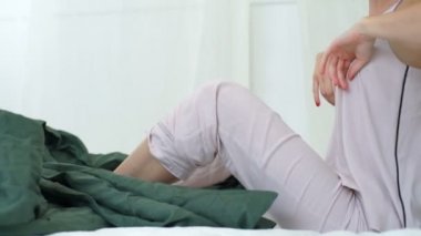 Young beautiful brunette girl in sleepwear stretching in bed after awake