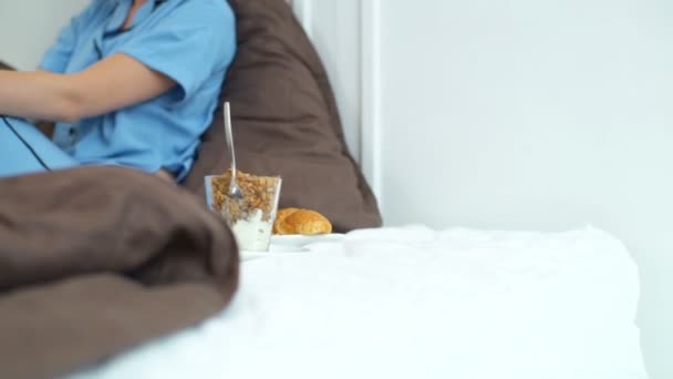Schöne Frau im Pyjama wird im Bett frühstücken — Stockvideo