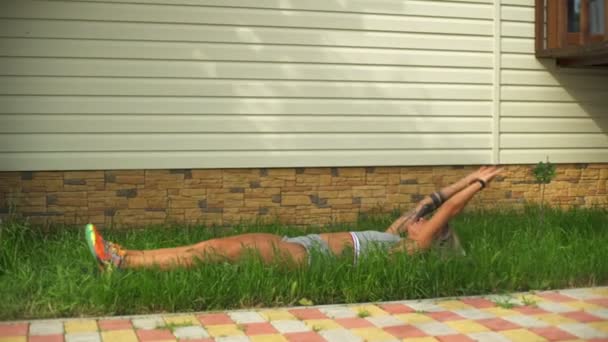 Young fit woman doing v-up on a green lawn — Stock Video