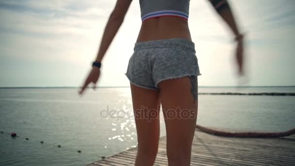 Młoda kobieta robi ćwiczenia jumping jack na plaży zbliżenie zwolnionym tempie sprawny — Wideo stockowe