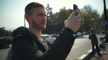 Bir akıllı telefon ile fotoğraf çekme ve yavaş hareket gülümseyen genç yakışıklı adam