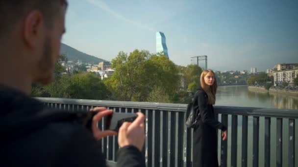 Junger, gutaussehender Mann fotografiert ein Mädchen mit einem Smartphone in Zeitlupe — Stockvideo