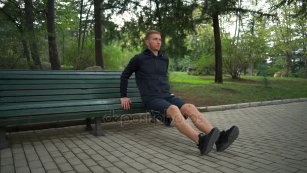 Uomo con uno stile di vita sano che fa flessioni panchina nel parco cittadino slow motion — Video Stock