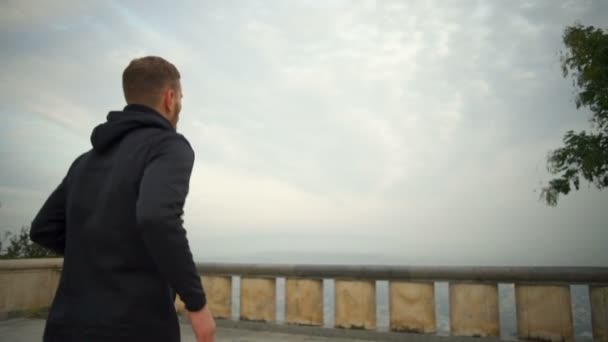 Ung man med hälsosam livsstil kör och höja hans arm slowmotion — Stockvideo