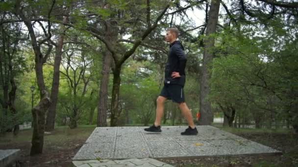 Mannen med hälsosam livsstil gör framåt utfall i city park slow motion — Stockvideo