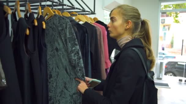 Młoda piękna kobieta i mężczyzna patrząc na ubrania w sklepie — Wideo stockowe