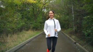 Koşu ve park ağır çekimde gülümseyen genç uygun sağlıklı bir kadın