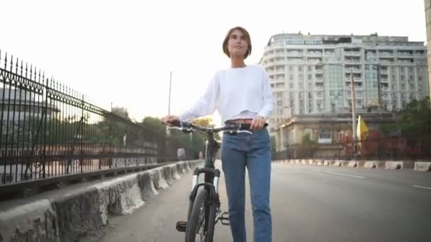 Atraktivní žena chodí po ulici nesoucí své kolo — Stock video