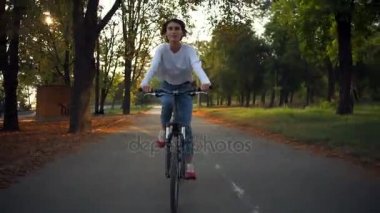 Önden Görünüm çekici mutlu erkek sabah parkın içinden bir bisiklet sürmek
