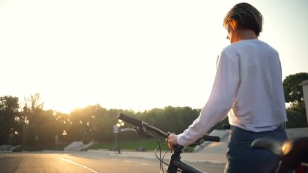 Junge Frau telefoniert im Park neben ihrem Fahrrad — Stockvideo