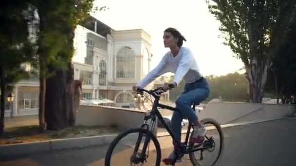 Aantrekkelijke vrouw een fiets in de ochtend park — Stockvideo