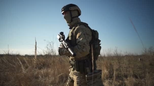 Солдат Airsoft с винтовкой и боеприпасами НАТО идет по полю — стоковое видео