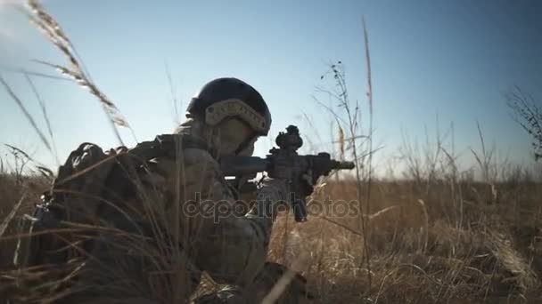 Airsoft soldier squats down and aims with a rifle and full NATO ammunition — Stock Video