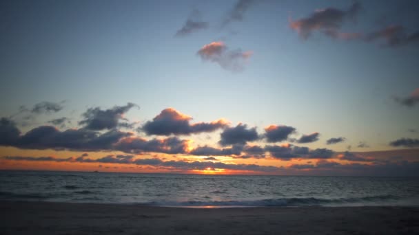 Un beau lever de soleil sur la plage avec des couleurs étonnantes et de petites vagues au ralenti — Video