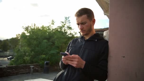 Un joven con barba usando su smartphone en la calle cámara lenta — Vídeo de stock