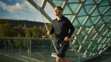 Modern köprü ağır çekim arasında çalışan kulaklıklar ile yakışıklı delikanlı