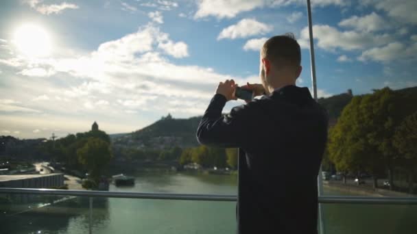 Mladý muž, stojící na krásném mostu a s foto zpomalené — Stock video