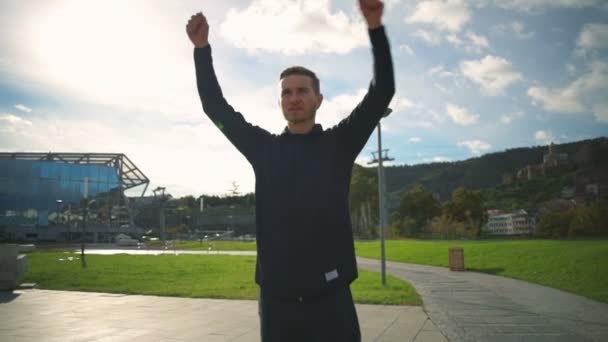 Joven hombre en forma calentando hombros en el hermoso parque de cámara lenta — Vídeos de Stock