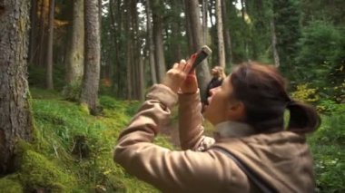 Genç bir kadın bir smartphone yavaş hareket ile güzel bir ormandaki fotoğraf çekme