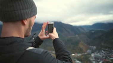 Bir smartphone yavaş hareket ile güzel dağlarının alarak fotoğraf genç adam