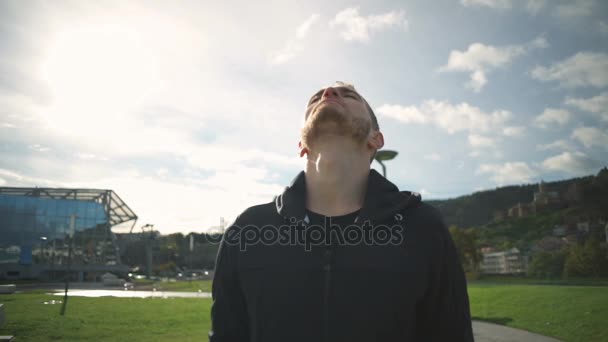 Hombre joven calentando, girando el cuello y la cabeza en el hermoso parque de cámara lenta — Vídeos de Stock