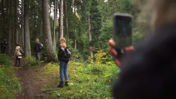 En ung kvinna att ta foto av hennes vänner i en vacker skog slow motion — Stockvideo