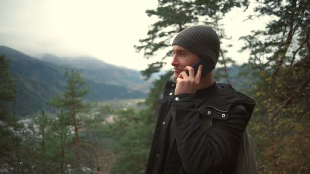 Молодий красивий маневр розмовляє по телефону в прекрасному лісі — стокове відео