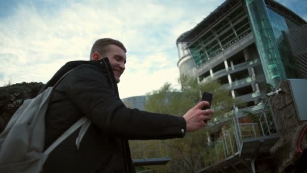 Молодой человек снимает видео необыкновенной красивой замедленной съемки здания — стоковое видео