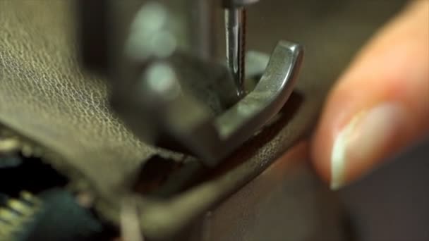 Zeitlupe einer Frau, die mit einer alten Nähmaschine ein Stück Leder von Hand näht