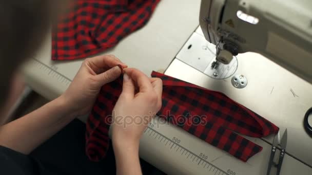 Una giovane donna cuce parti di stoffa con ago e filo — Video Stock