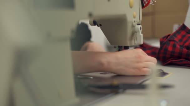 Una joven costurera cosiendo ropa y cortando con tijeras — Vídeo de stock