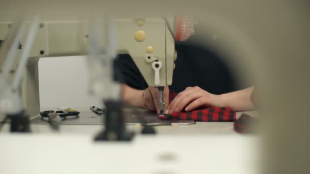 Una giovane donna cuce accuratamente i vestiti con una macchina da cucire — Video Stock