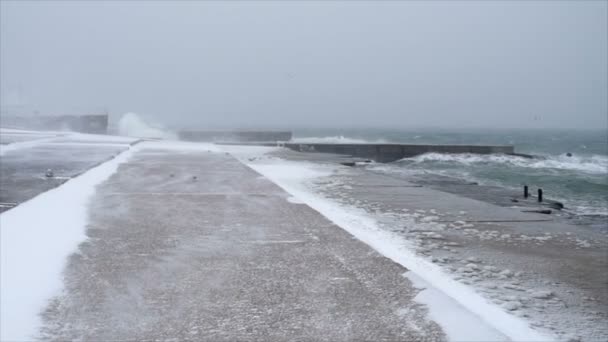 Zăpada acoperă coasta de beton cu un val uriaș pe fundal — Videoclip de stoc