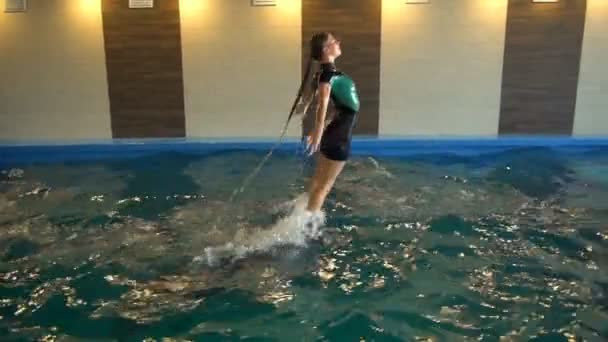 Тамер выскакивает из воды, стоя на носу дельфинов, замедленное движение — стоковое видео