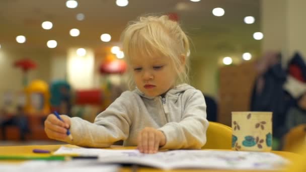 Adorable niña rubia gira la página del libro para colorear cámara lenta — Vídeos de Stock