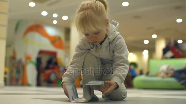 Linda niña jugando con un libro para colorear y que se levanta y se va — Vídeo de stock