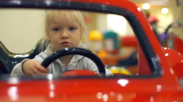 Söta lilla blonda flickan kör röd leksaksbil och ha roligt långsam rörelse — Stockvideo