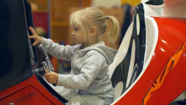 Petite fille mignonne assise dans la voiture de sport jouet et direction au ralenti — Video